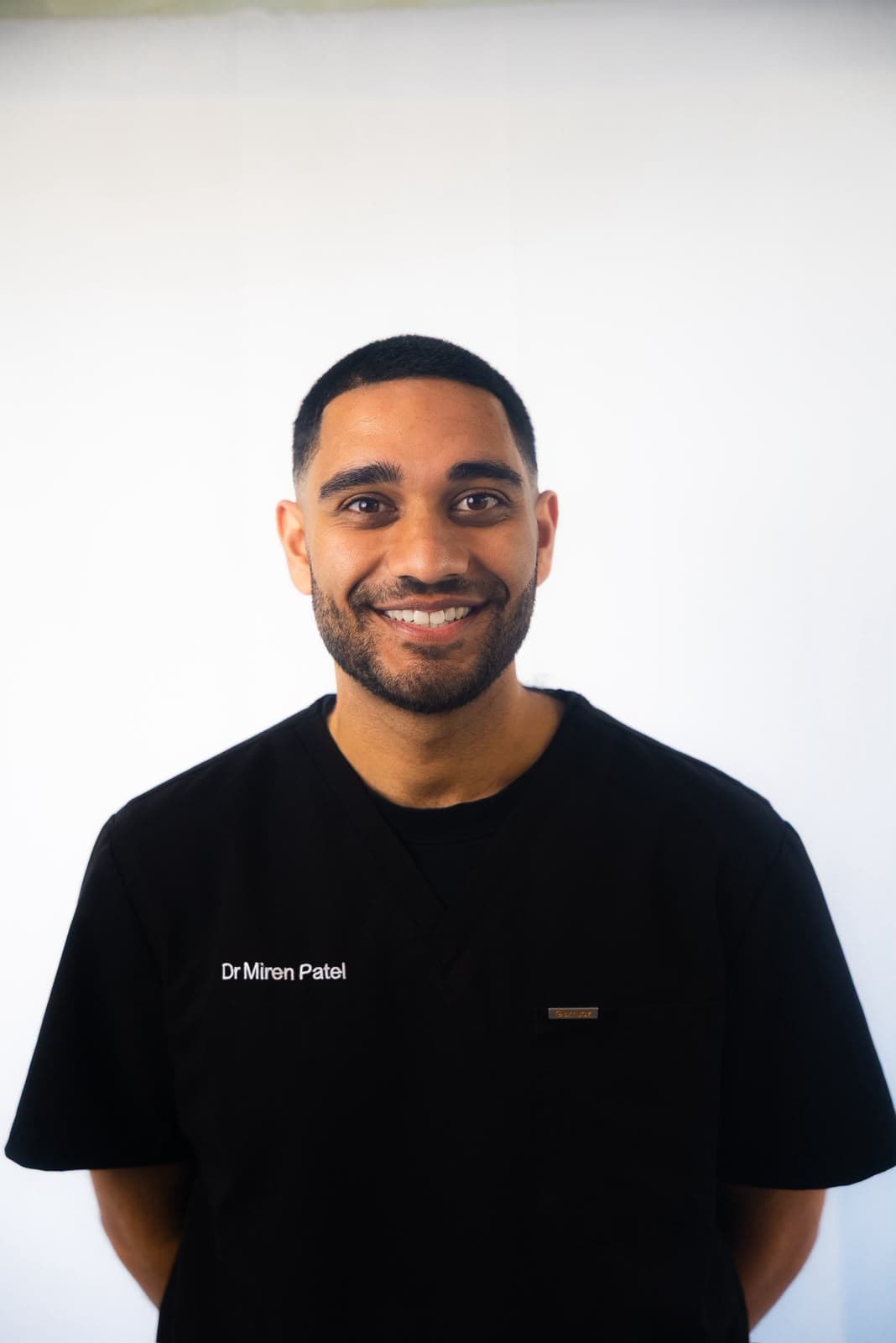 Miren Patel, smiling, in black scrubs